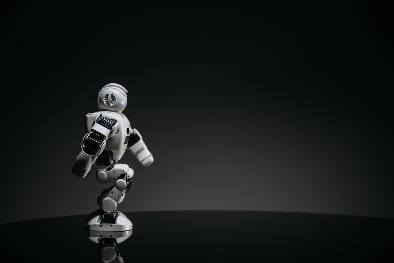 A sleek white toy robot poised elegantly against a dark studio backdrop.